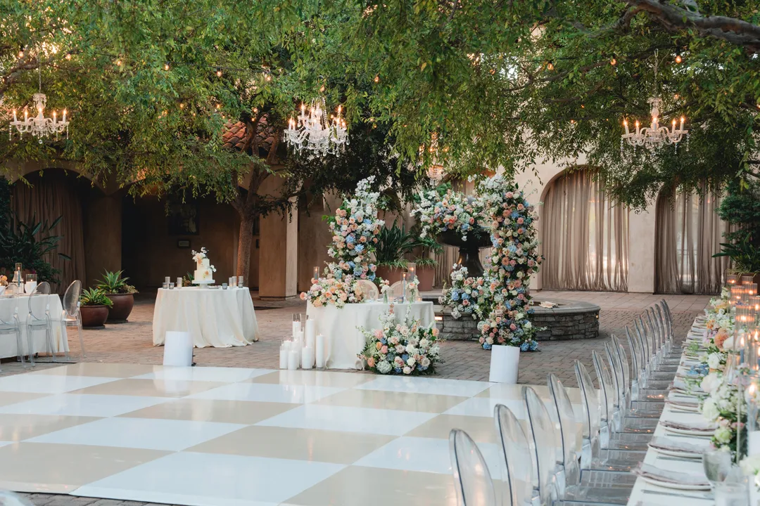 Pastel floral sweetheart table beside the pale checkered dance floor at Serra Plaza.