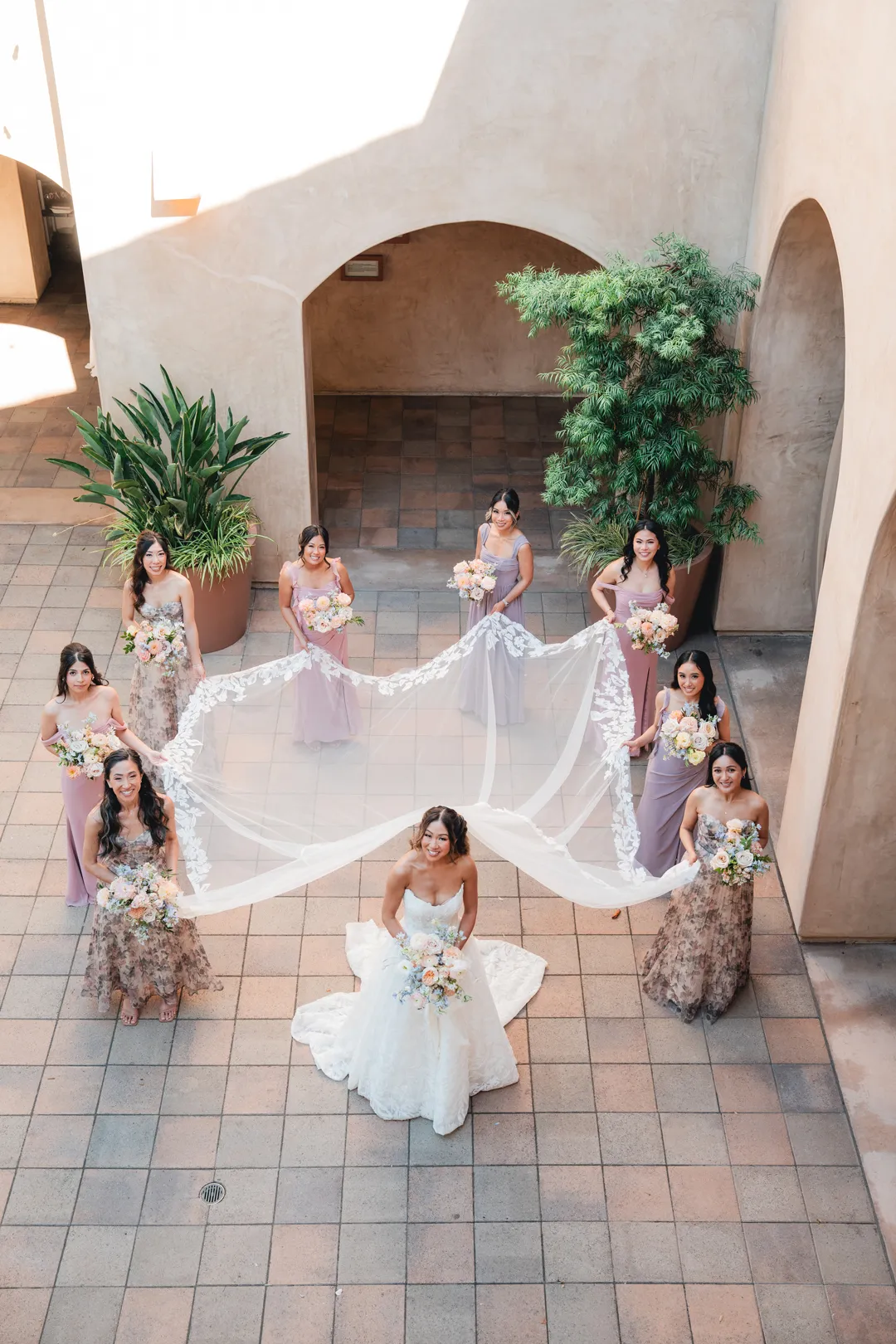 Bridesmaids arranging the bride's long veil in the Serra Plaza courtyard.