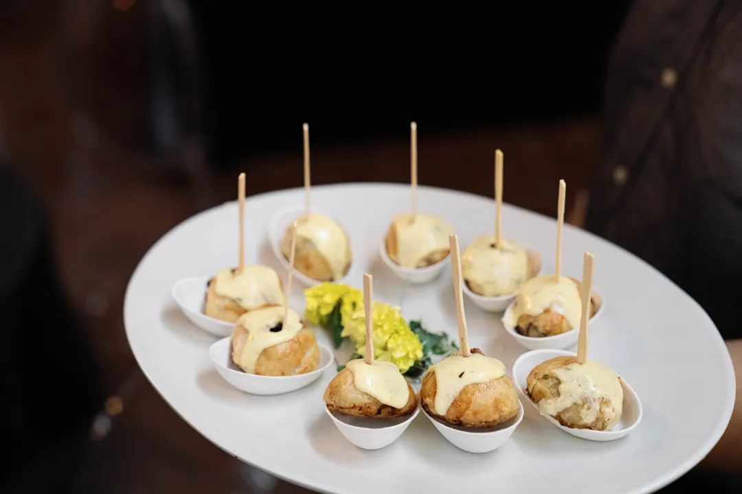 Small appetizers in individual spoons topped with creamy sauce.