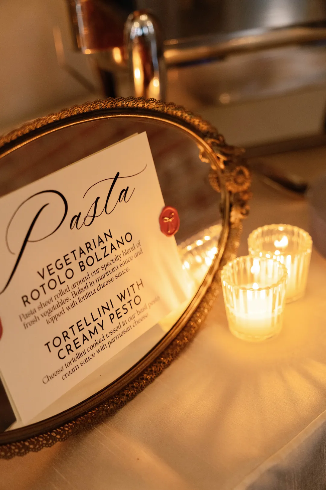 Vegetarian Rotolo Bolzano and Tortellini with Creamy Pesto menu beside a candle.