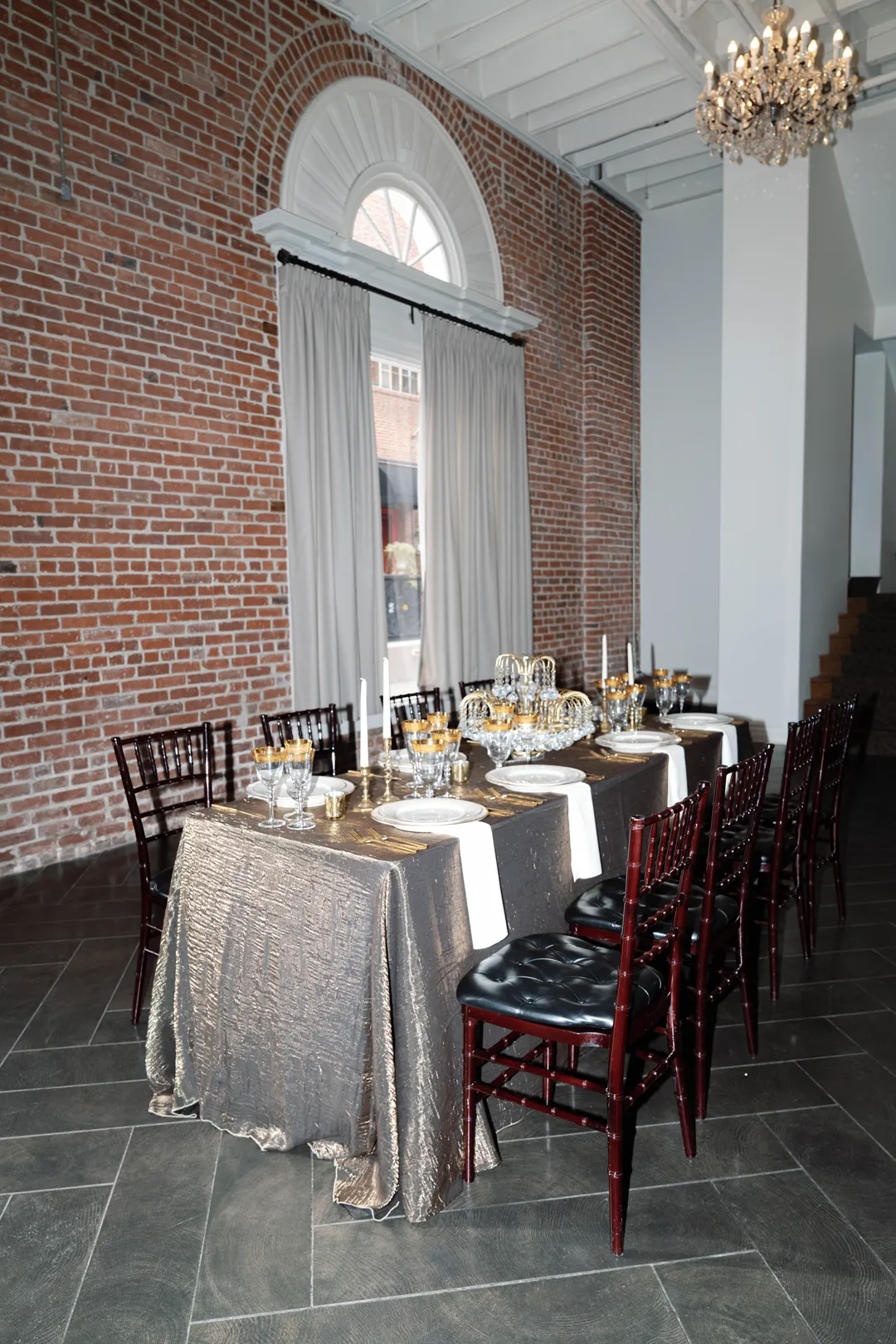 Long dining table beside The Estate on Second's arched windows and exposed brick.