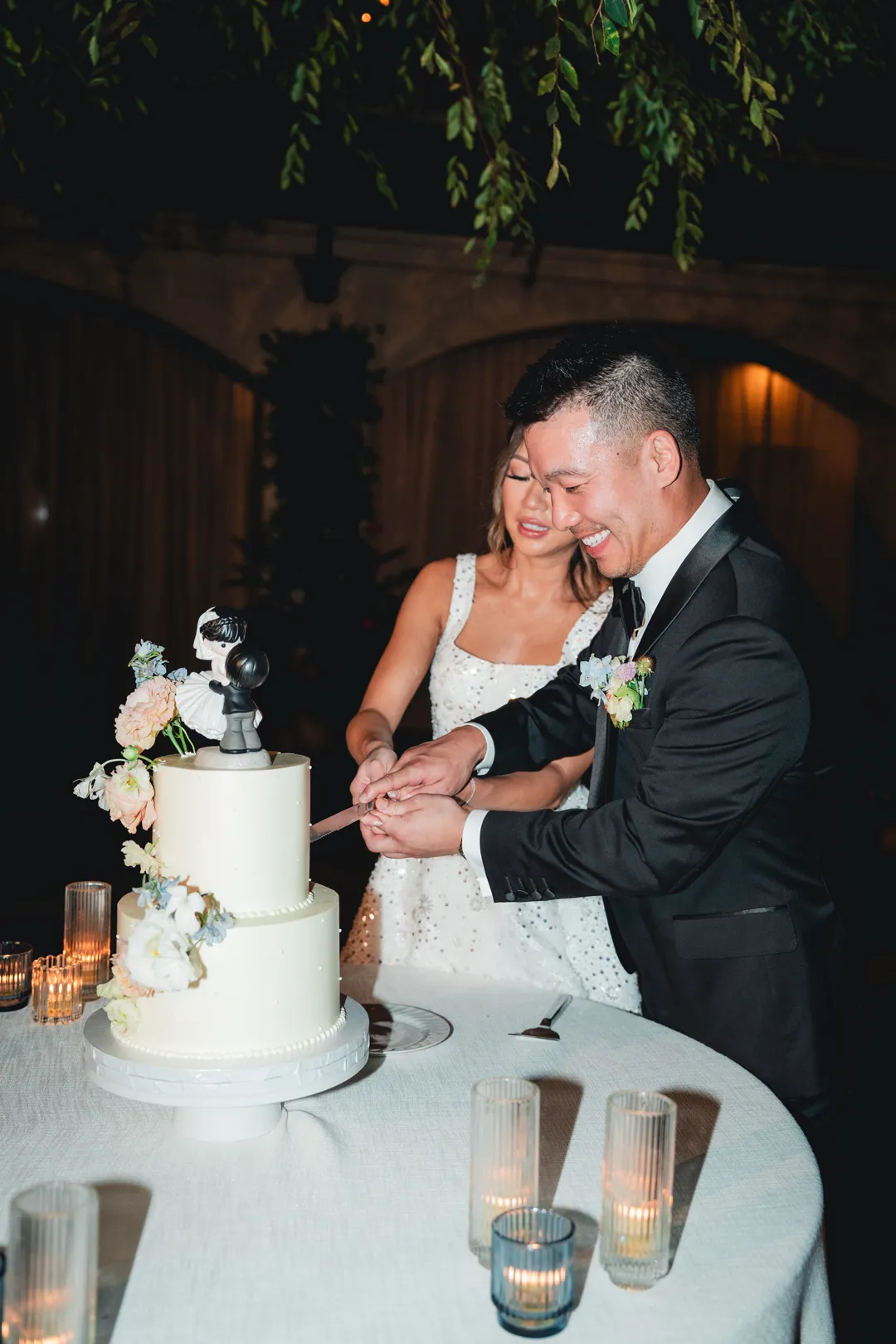Newlyweds cutting their Jay's Catering wedding cake by candlelight at Serra Plaza.