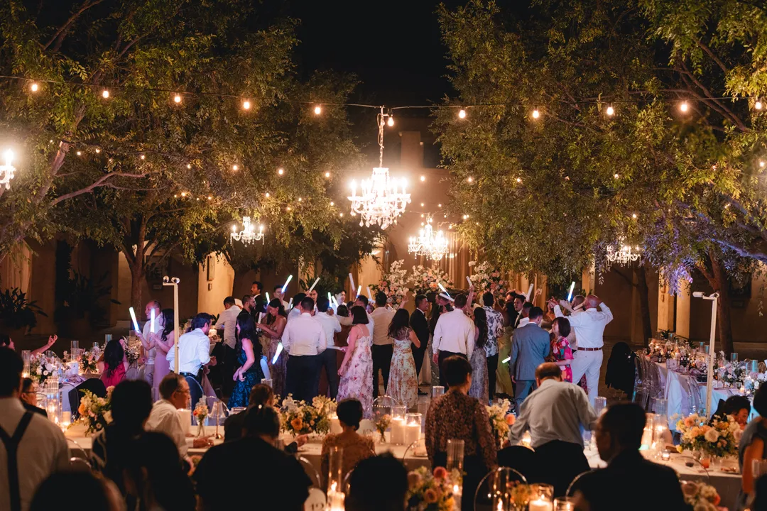 Wedding guests dancing beneath Serra Plaza's courtyard chandeliers and string lights.