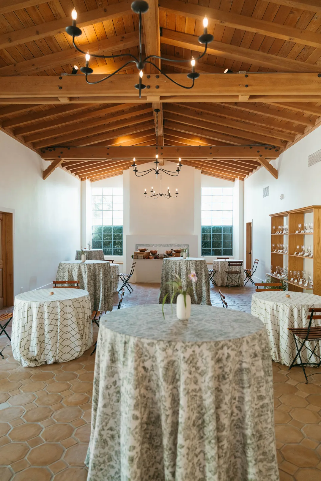 Patterned-linen cocktail tables beneath Grand Gimeno's wooden ceiling and chandeliers.