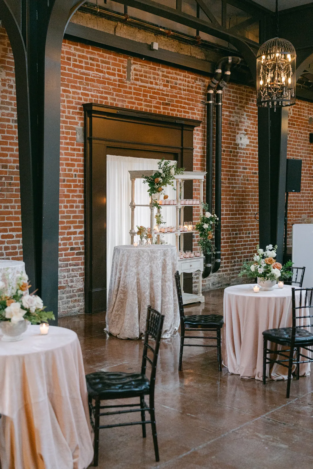 Cocktail tables and floral decorations against The Estate on Second's exposed brick walls.