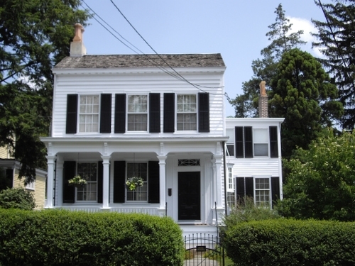 a white colonial home with black shutters on a sunny blue skied day