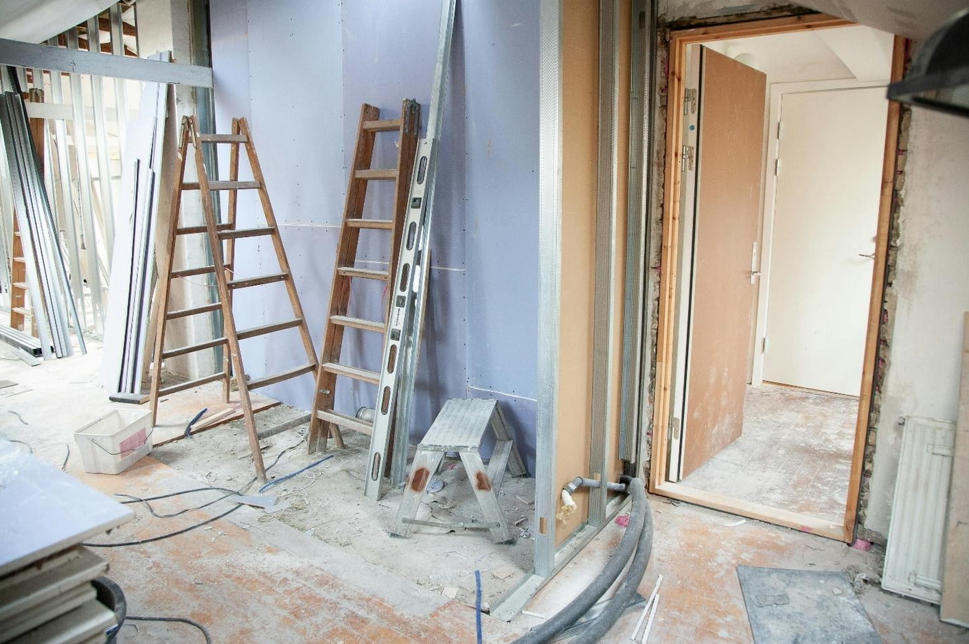 A room featuring a ladder leaning against the wall, with another ladder positioned in the center of the space.