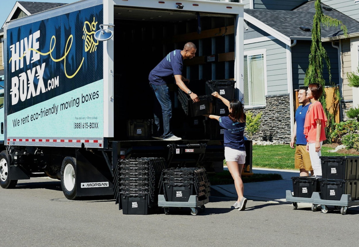 A man and woman are loading boxes into a moving truck, preparing for their relocation.