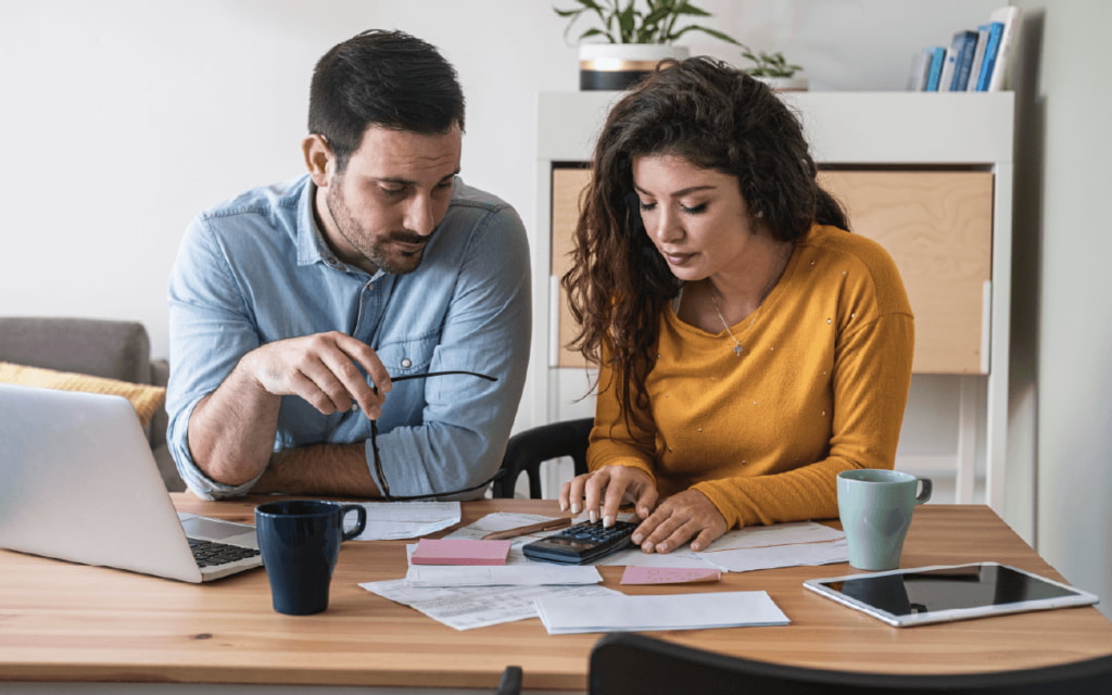 A man and woman sit at a table, reviewing paperwork together with focused expressions.