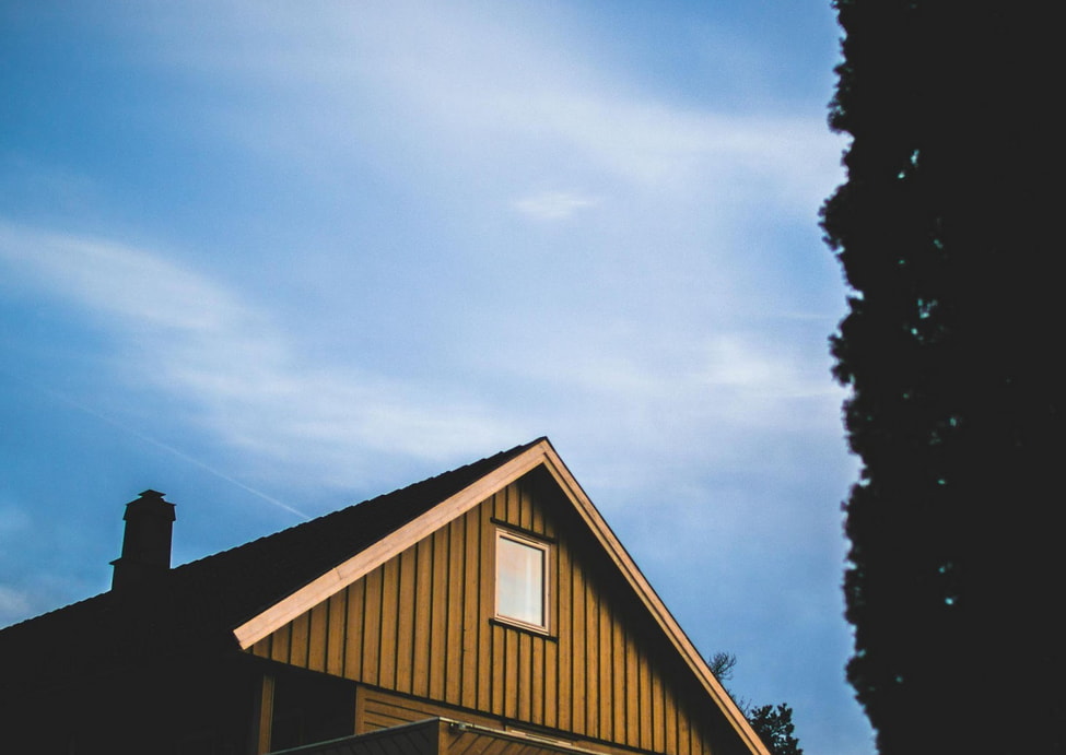 A house is set against a bright blue sky, featuring a tree in the background.