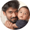 An Indian man with facial hair holding his baby