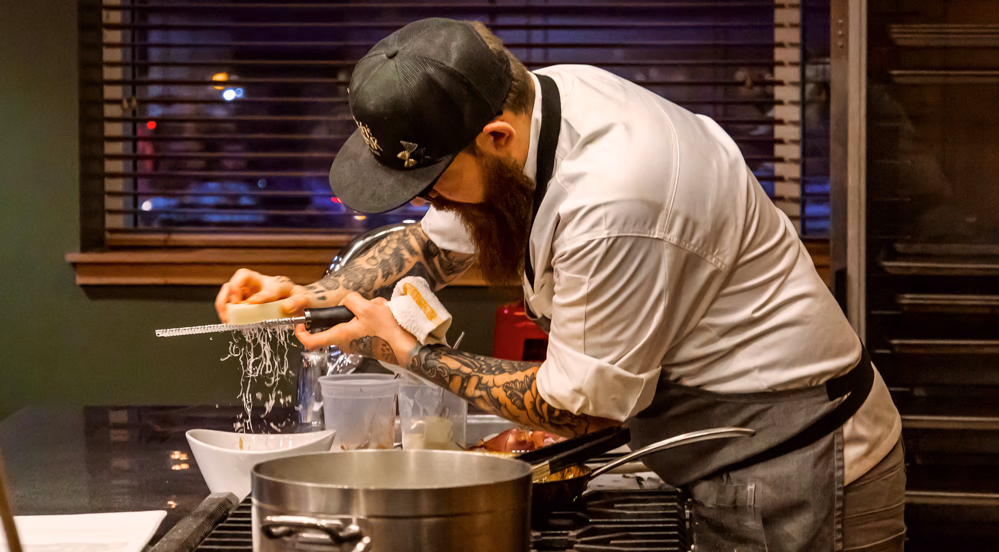 Chef Adam Pawlak, grating cheese while leading a cooking class for Milwaukee Public Market.
