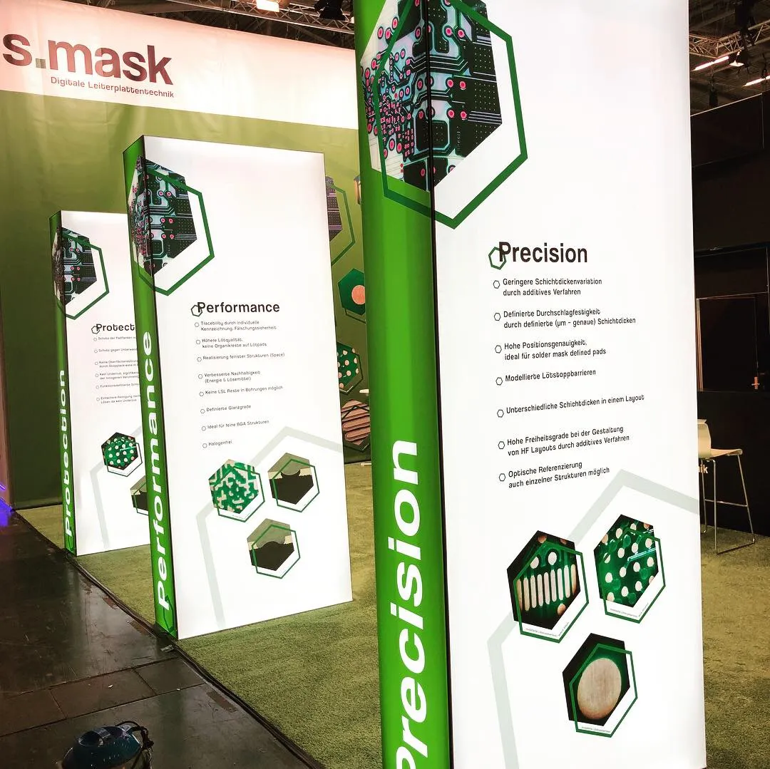 Messestand mit grünen und weißen vertikalen Bannern zu den Themen Präzision, Leistung und Schutz in der Leiterplattentechnik.