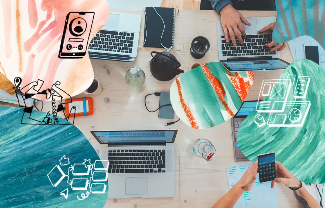 a photo of a bird's eye view of a table crowded with open laptops, notebooks, and beverages