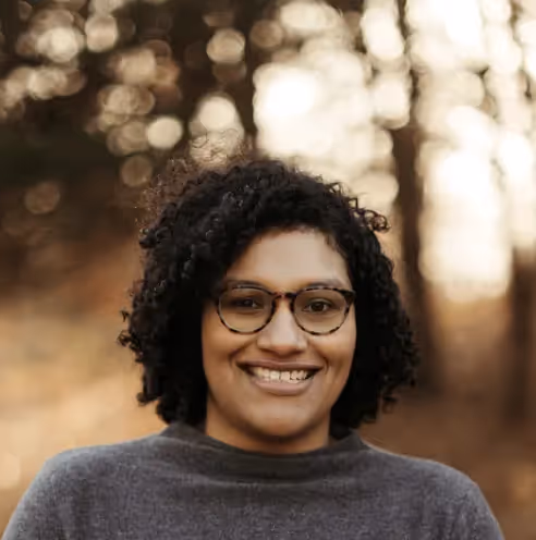 roberta dombrowski headshot - woman with short curly hair in gray shirt against blurred background
