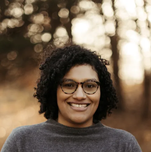 roberta dombrowski headshot - woman with short curly hair in gray shirt against blurred background 