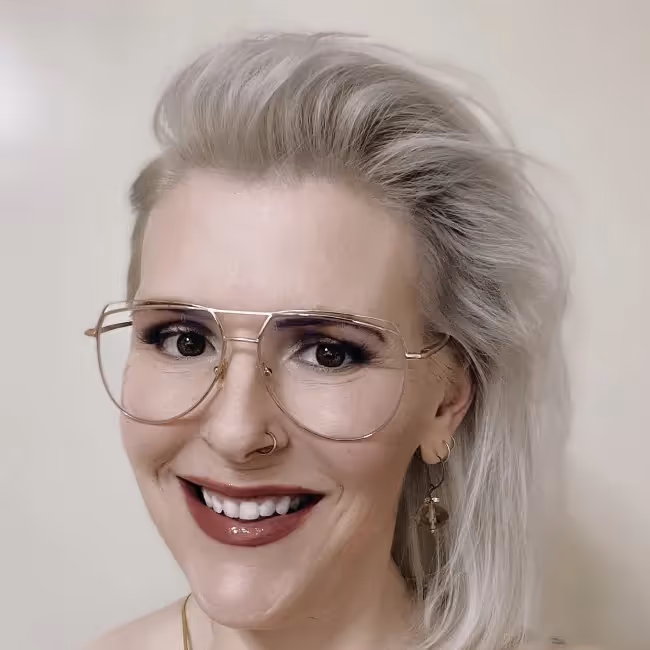 holly cole headshot - woman with silver hair glasses and red lipstick smiling against white background