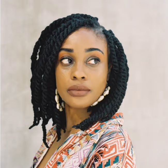 Jacquelyn Iyamah headshot - woman in colorful shirt looking off to the side against a gray background