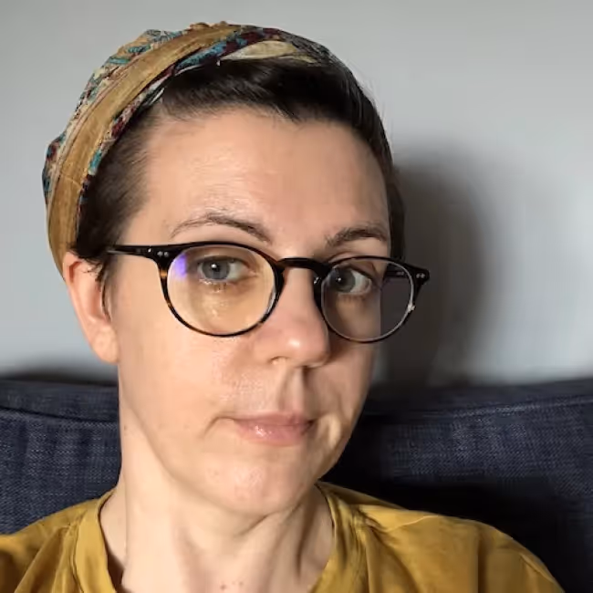 stephanie marsh headshot - woman with hair pulled back and glasses in yellow shirt against white and black background