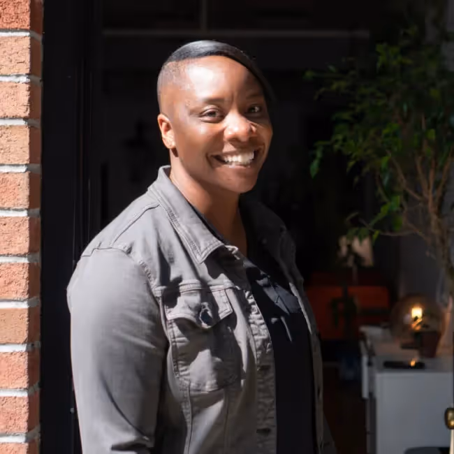 vivianne castillo background - woman in grey shirt standing against dark background