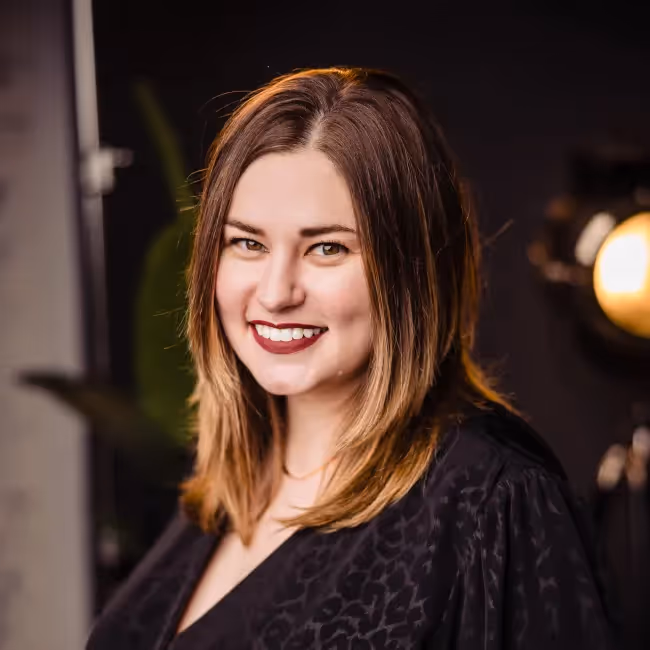 kasey canlas headshot - woman with long light brown hair smiling against dark blurred background