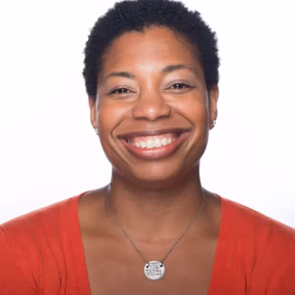 regine gilbert headshot - woman in red shirt against a white background