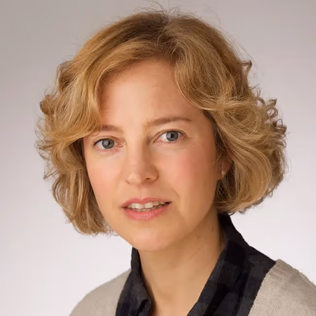 kate towsey headshot - woman with short blonde hair against a grey background