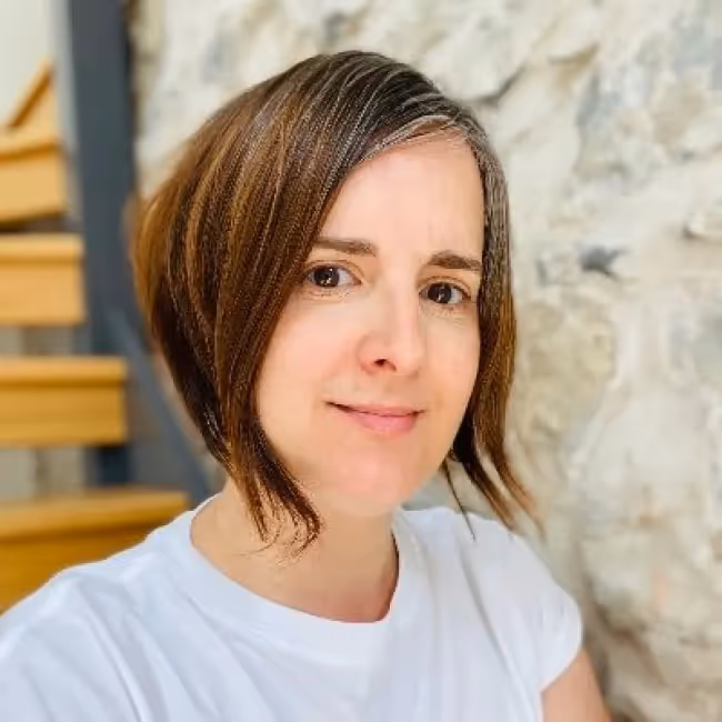 emma boulton headshot - woman with short brown hair in white tshirt against background of stairs and stone wall