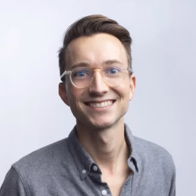 lucas puente headshot - man with clear glasses against a gray background