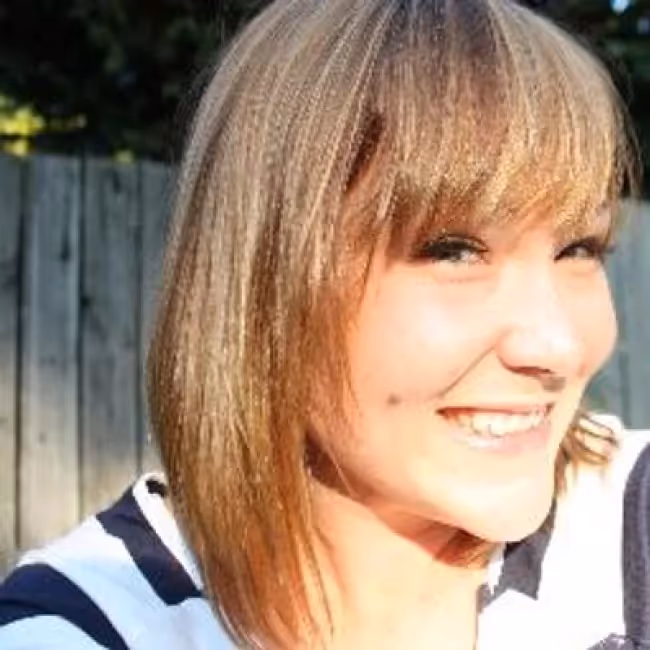 noel lamb headshot - woman with blonde hair and bangs in blue and white striped shirt