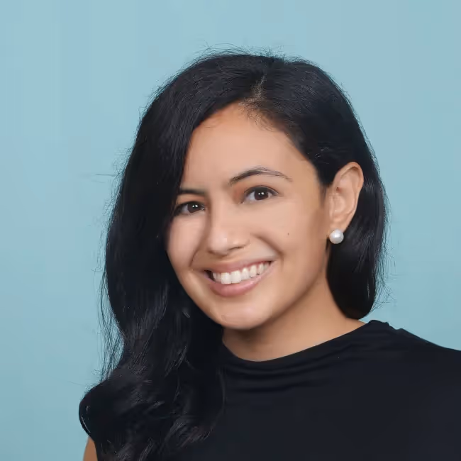 Pia Zaragoza headshot - woman with long dark hair and black shirt against light blue background