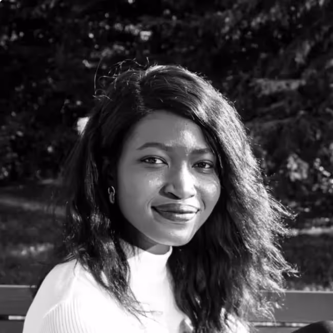 Toluwa Awodiya headshot - black and white photo of woman with long dark hair in white shirt against dark background