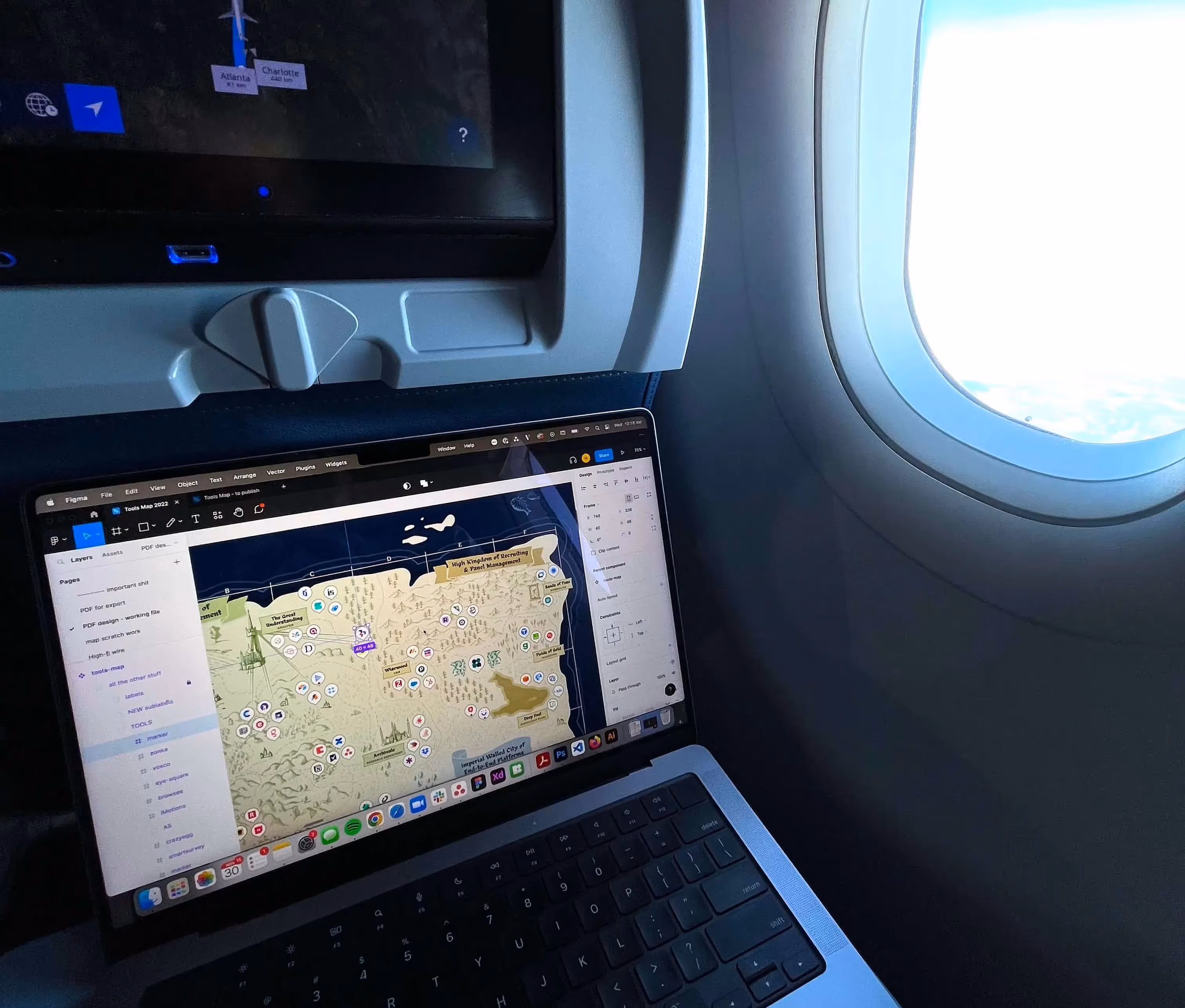 photo of a laptop open to a working figma, next to an airplane window