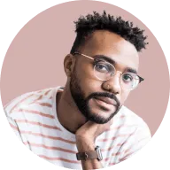 Man with glasses and short curly hair wearing a white and pink striped shirt on a light pink circular background.
