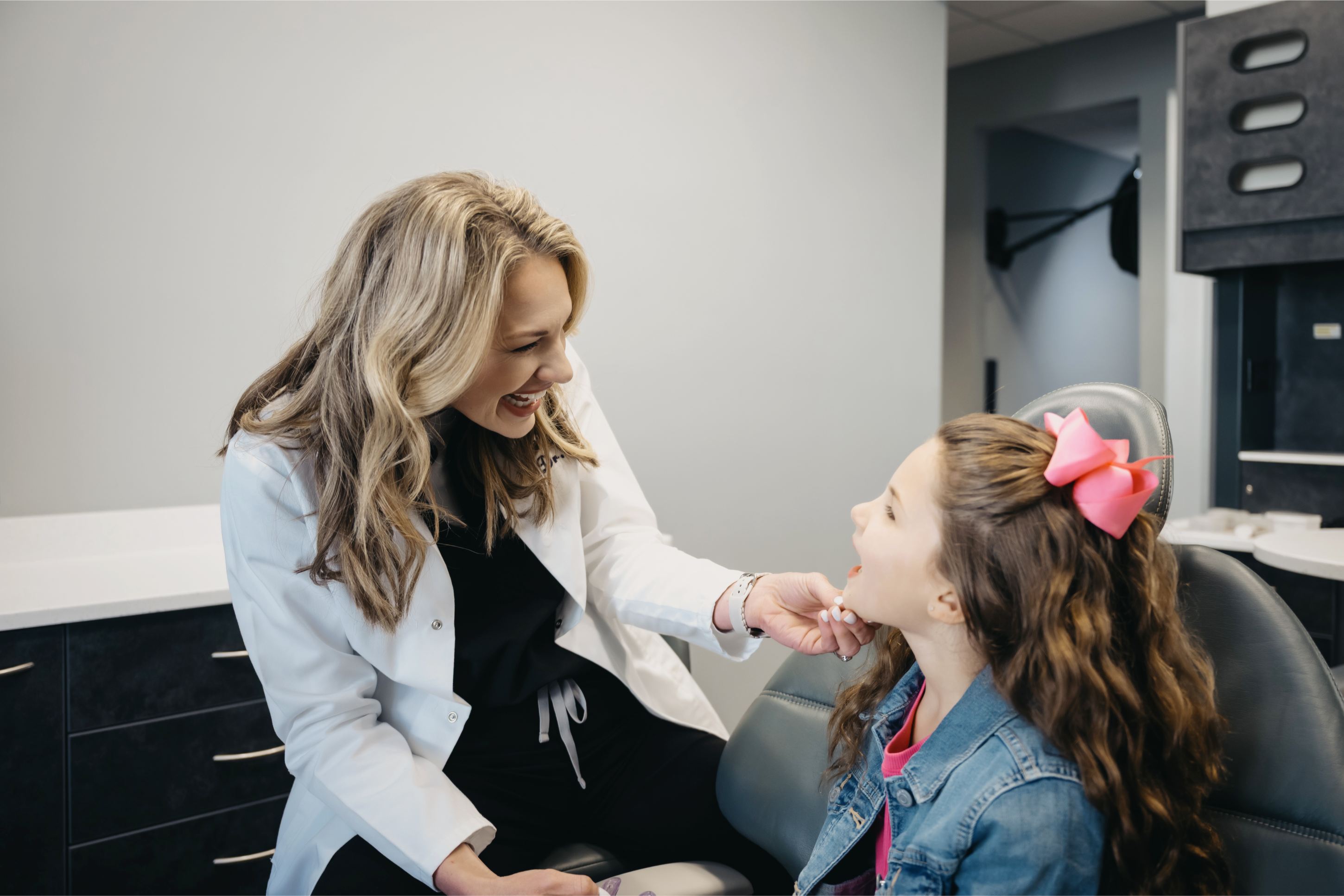 Dentist at Great Lakes Dental smiling and checking the smile of a little girl in their dental office.