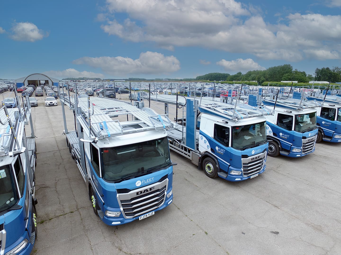 A close up of transporter lorries on a lot full of cars