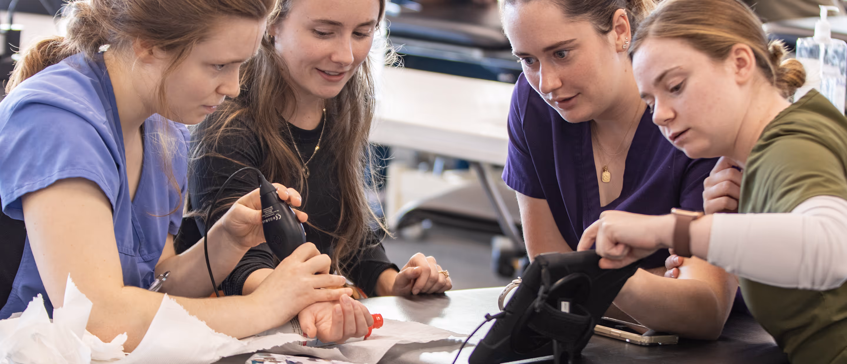 Four women closely examining a wrist with the butterfly iQ3