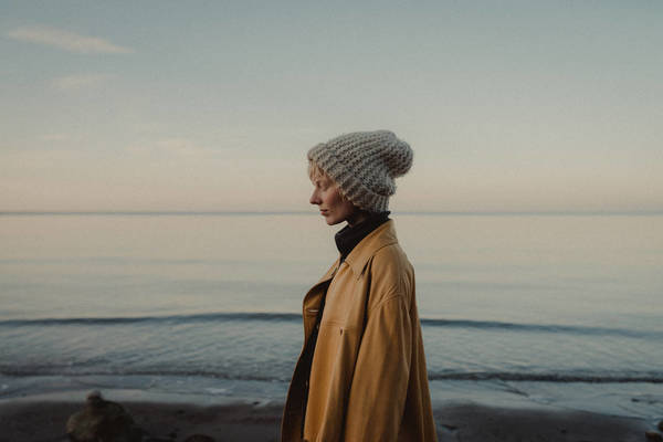 Woman Standing At Beach Against Sky During Sunset