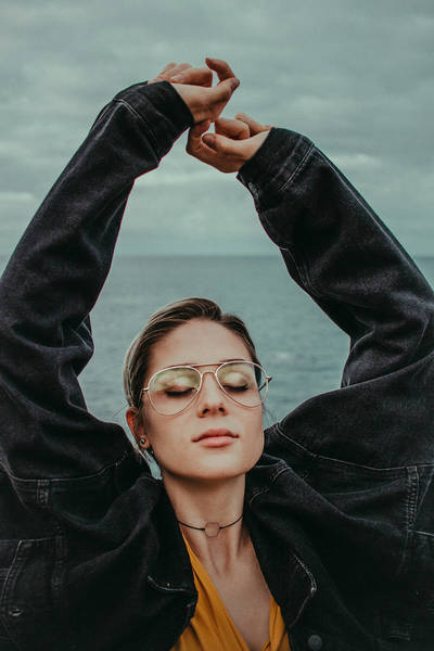Young Woman with arms raised standing at beach Against Sky