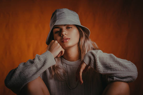 Portrait Of Young Woman In Hood Clothing Against Wall