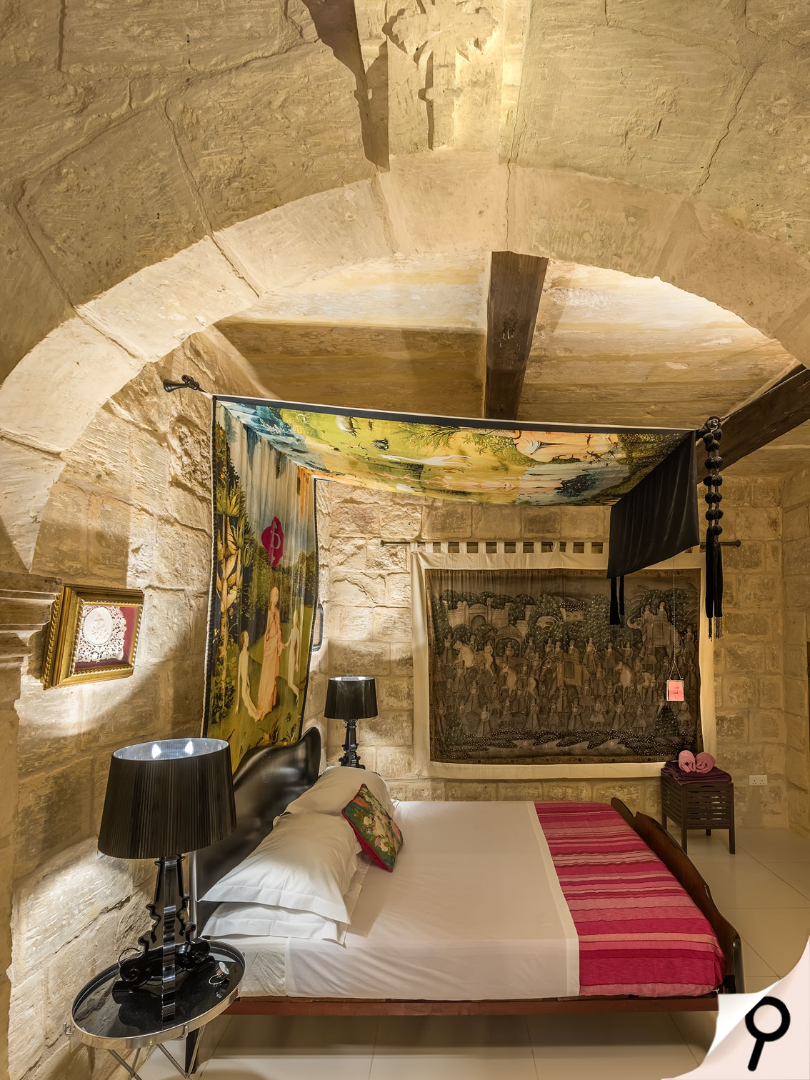 White door, plants in pots either side, lit by hanging lamps, sculptured stone banister in foreground. Malta holiday accommodation.