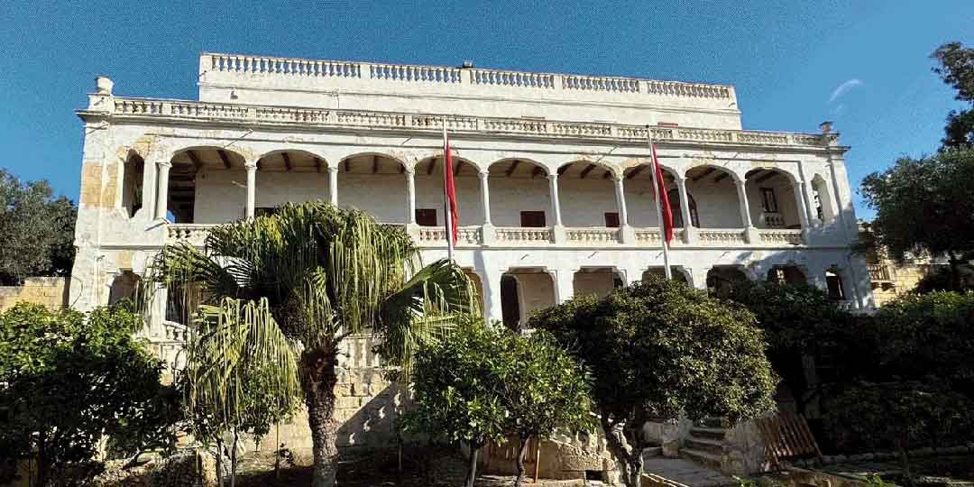 Villa Portelli with its white facade with arches and trees in the front garden