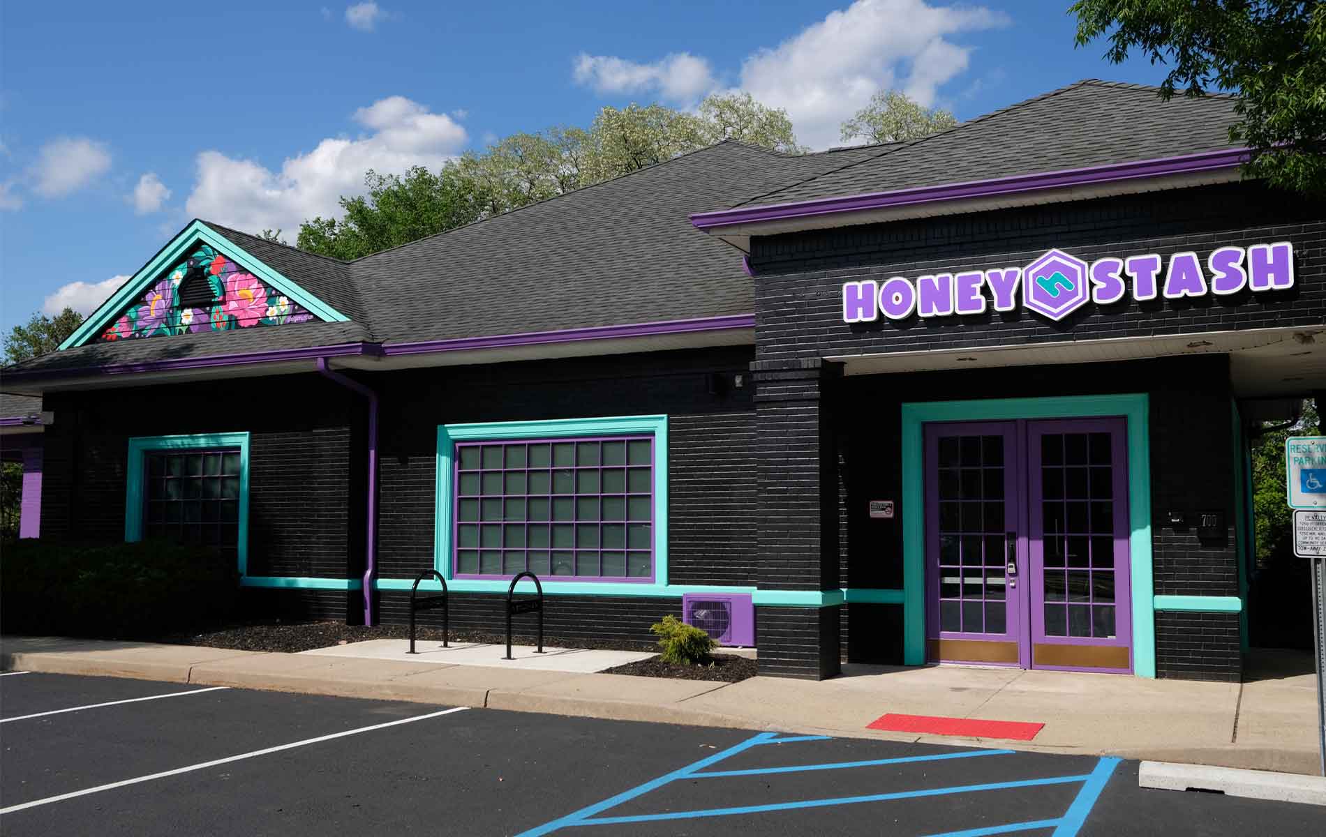 Exterior of the Honey Stash dispensary, a brick building painted black with teal trims 