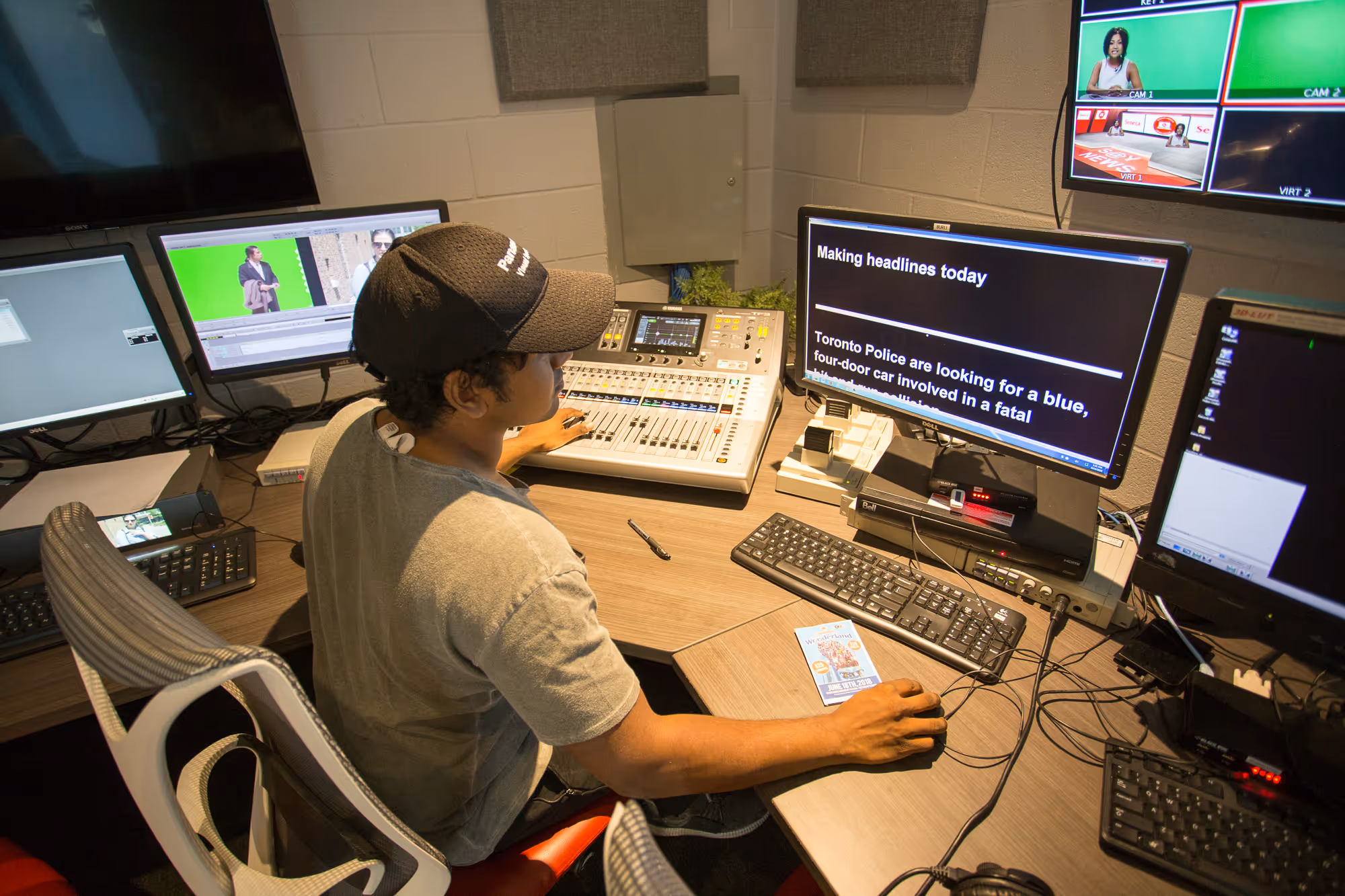 Student in a media broadcast studio working on a teleprompter surrounded by computers