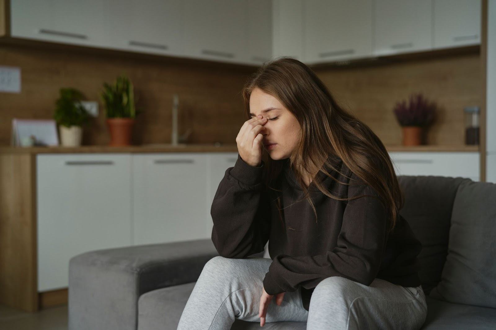 Young woman with sinus pain holding her nose at home