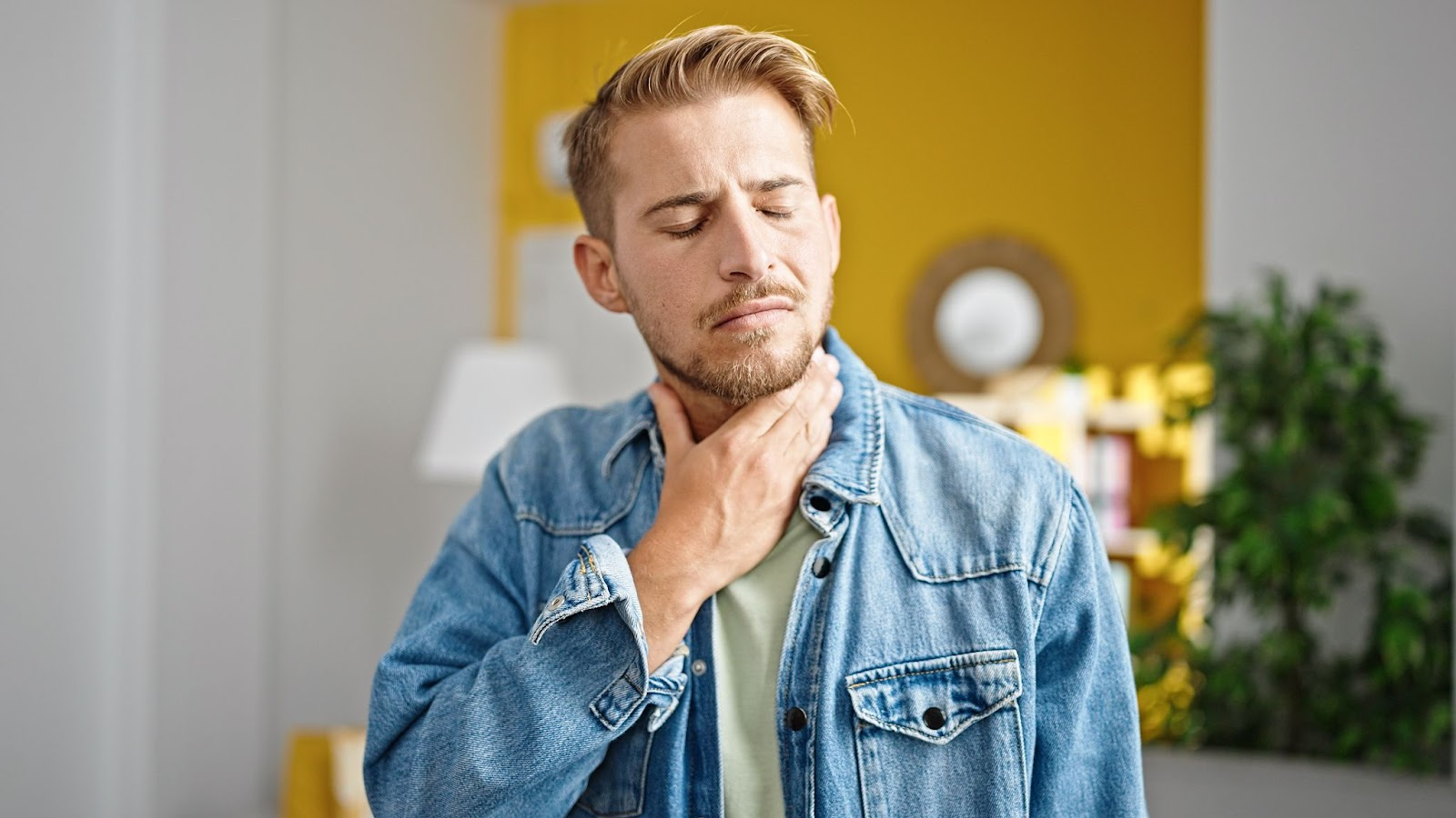 Man with sore throat touching his neck in discomfort