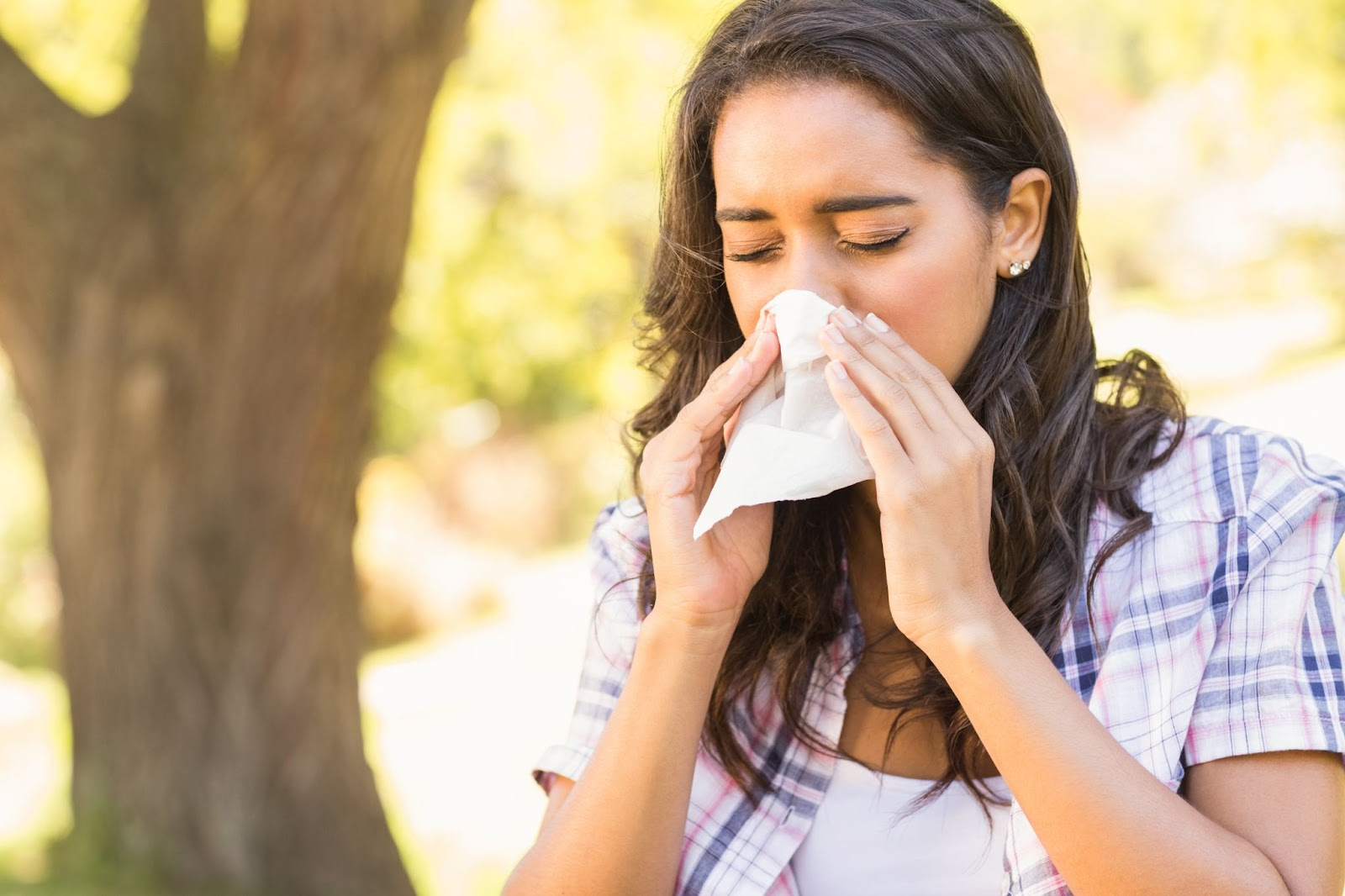 Woman sneezing outdoors from seasonal allergies