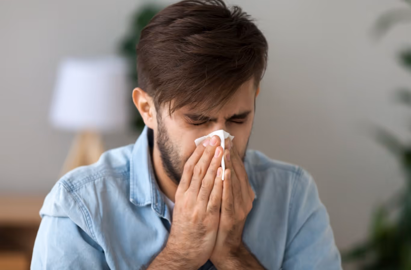 Man suffering from sinus congestion and facial pressure, holding tissue