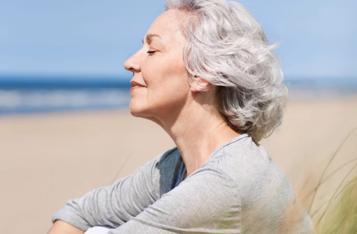 Senior woman enjoying clear breathing at the beach after sinus treatment