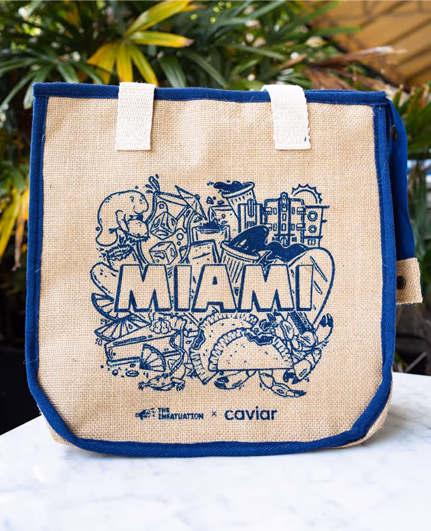 A promotional tote made for The Infatuation and Caviar. It says 'Miami' in block letters and shows lots of famous items from the Miami food scene: tropical drinks, key lime pie, empanadas, etc. 